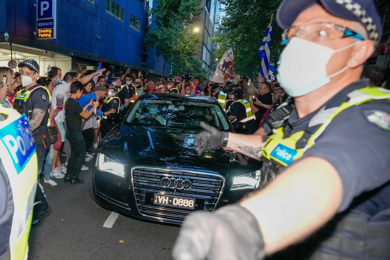 Police clear fans of Serbian Novak Djokovic as a car leaves the offices of lawyers following his court win ahead of the Australian Open in Melbourne, Australia, Monday, Jan. 10, 2022. An Australian judge has reinstated Djokovic's visa, which was canceled 