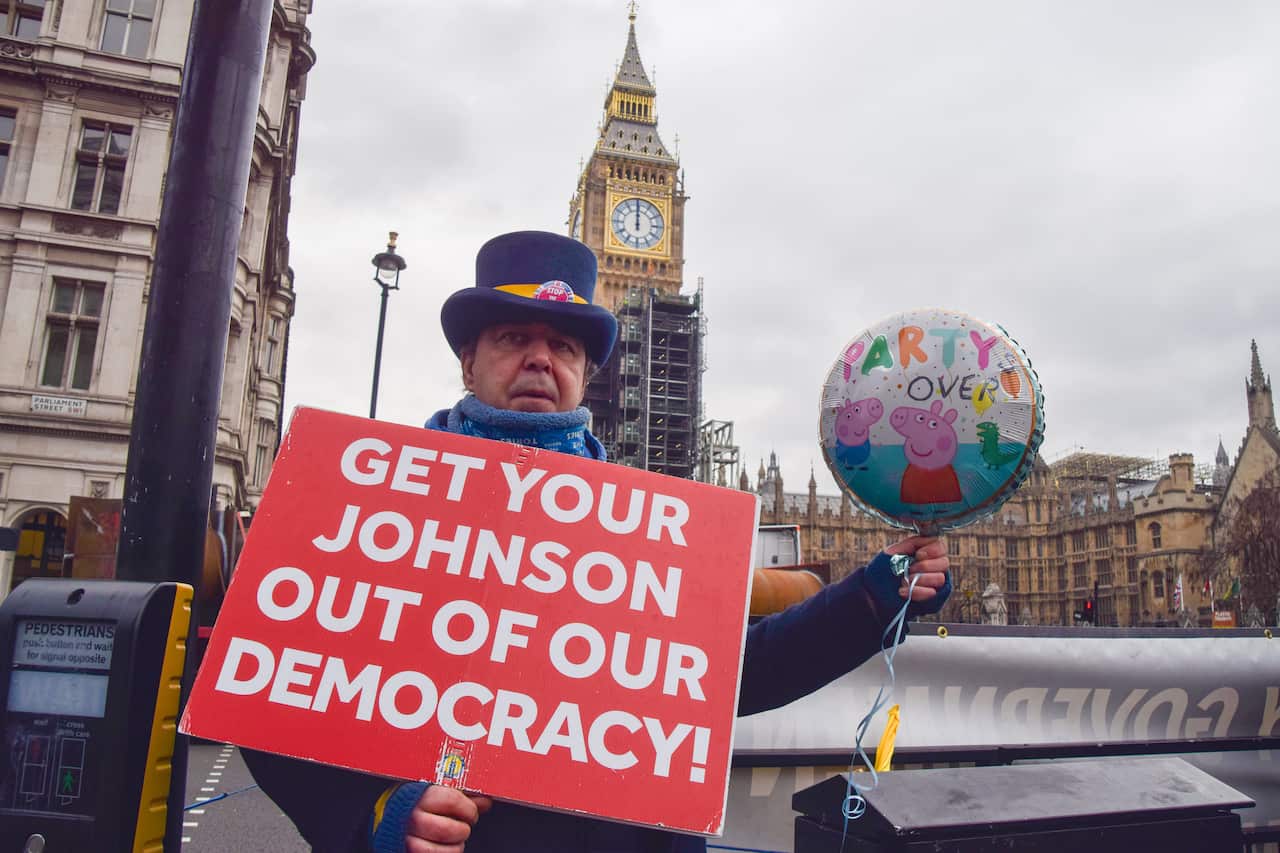 Activist Steve Bray holds an anti-Boris Johnson placard and a balloon with 'Party's Over' written on it, during a demonstration in London.