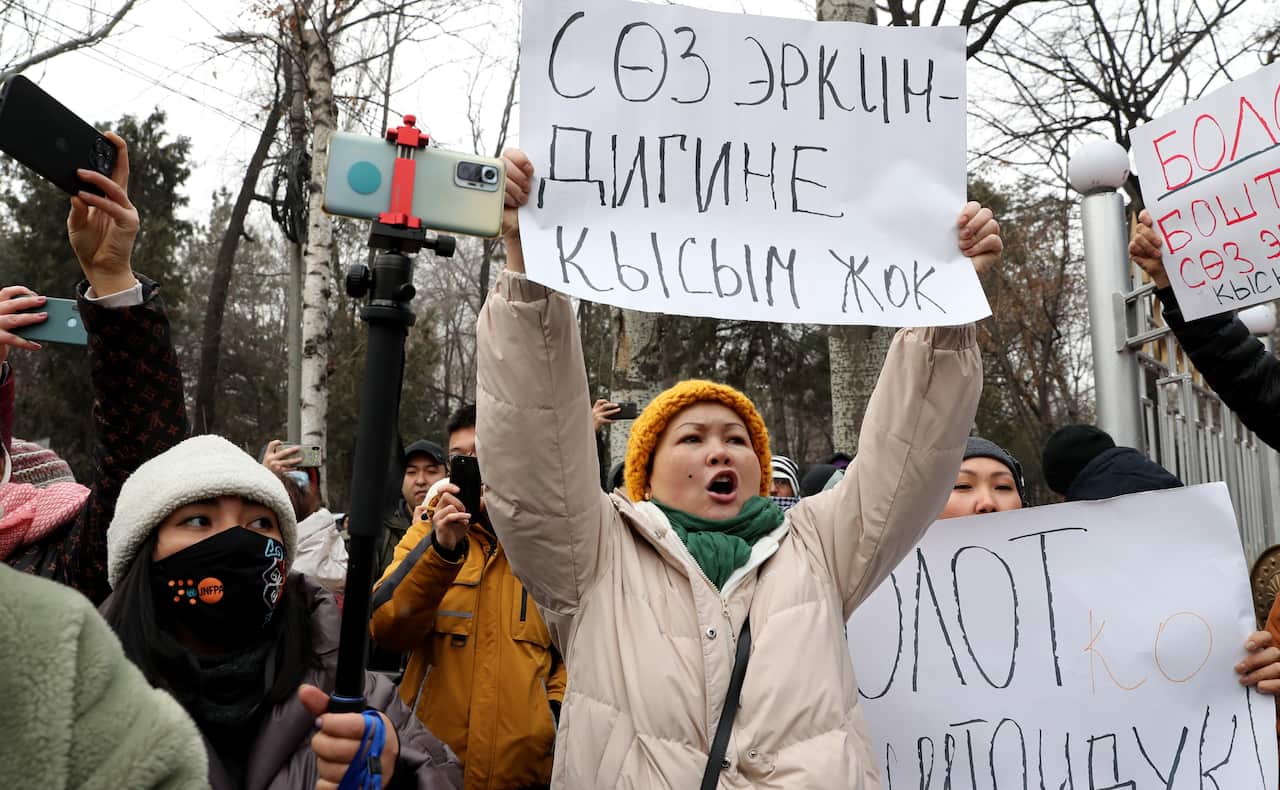 People hold placards as they gather for a rally in support of detained journalist Bolot Temirov.