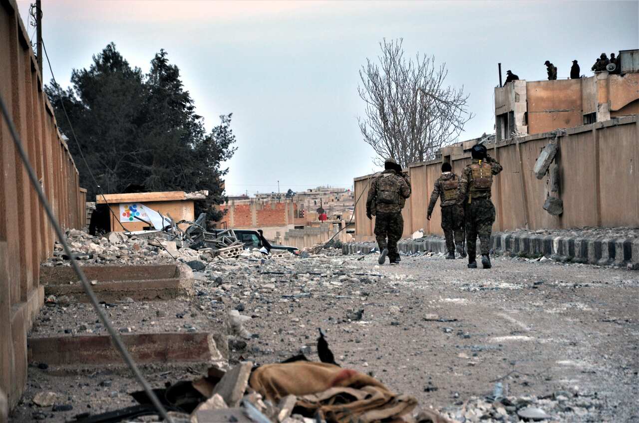 Fighters of Syria Democratic Forces (SDF) walk amid damage of Ghwayran prison in Hassakeh, northeastern Syria