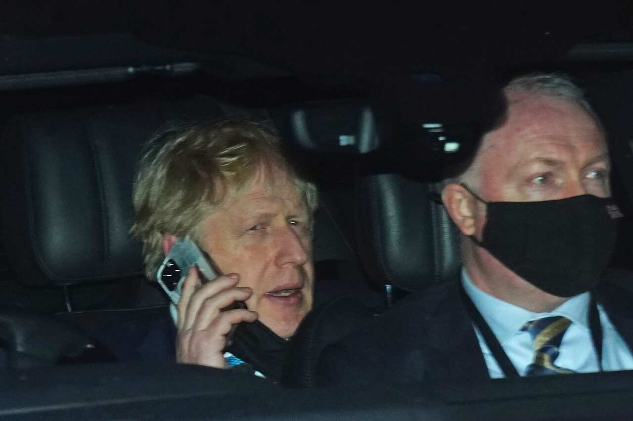 Prime Minister Boris Johnson (left) rides in the back seat of a government car while speaking on a mobile phone as he returns to Downing Street, London.