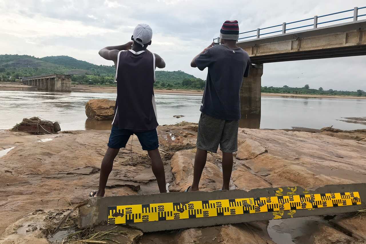 Two men take pictures of a destroyed bridge after Tropical Storm Ana hit the district of Tete, Mozambique.