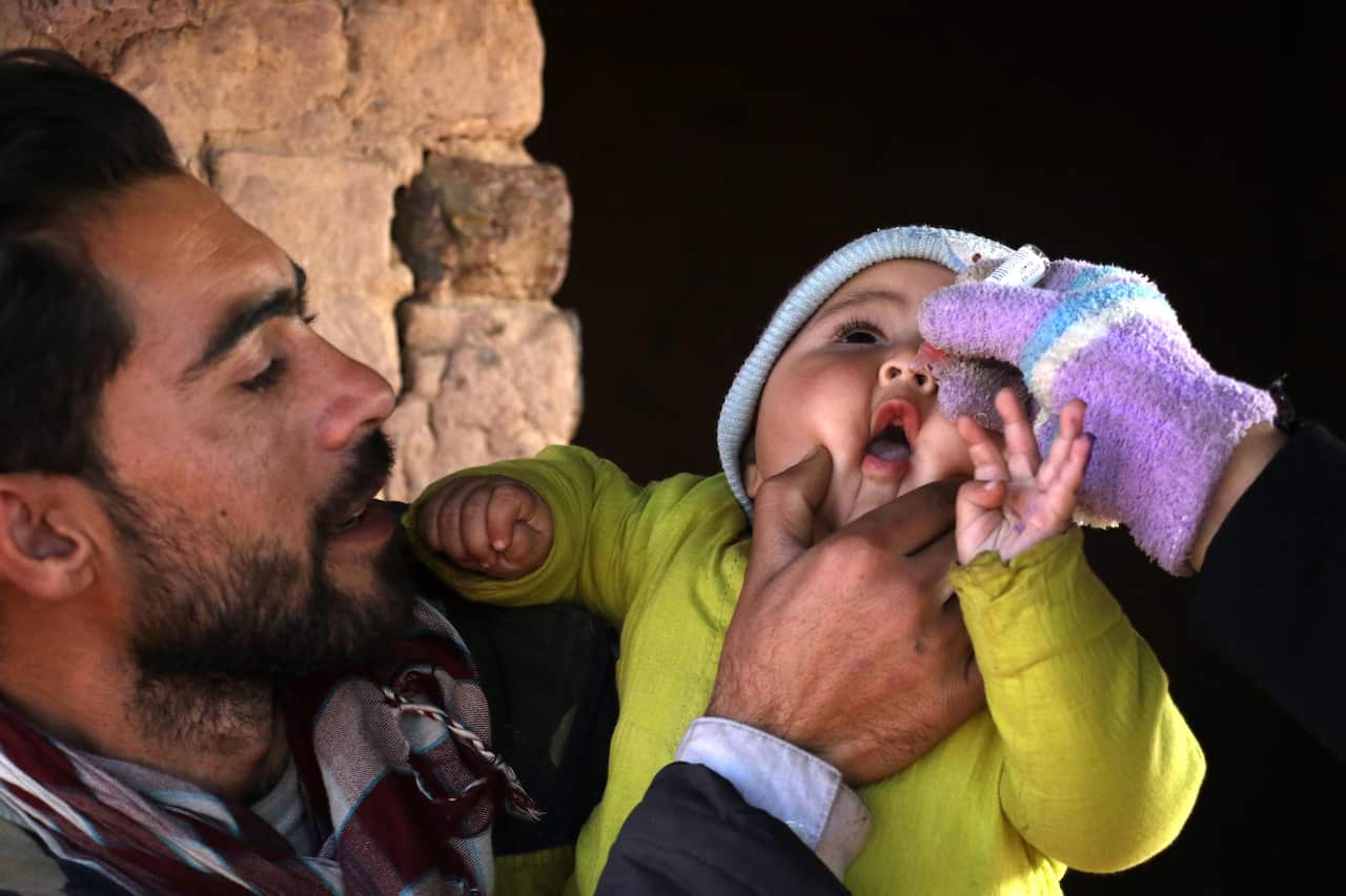 A health worker administers polio vaccine to an Afghan refugee at their camp on the outskirts of Islamabad, Pakistan in 2022.