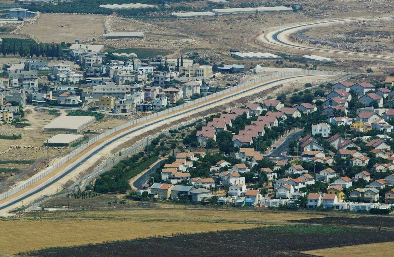 Aerial view over West Bank showing a Palestinian village, left, and a Jewish settlement, right, separated by part of the seperation fence, July 2003. 