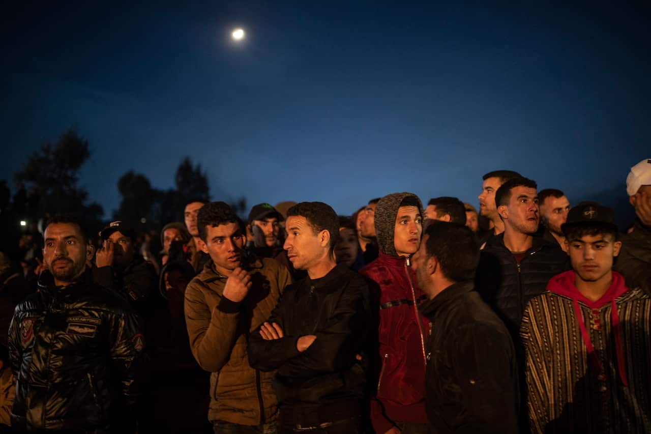 Residents observe civil defense workers and local authorities attempting to rescue a boy