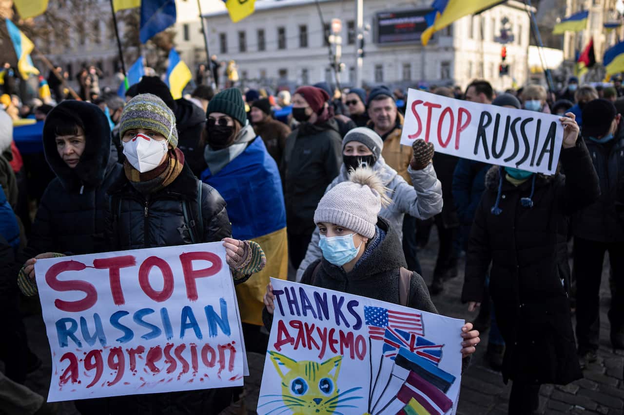 Demonstrators with Ukrainian national flags and posters march in the center of Kharkiv, 