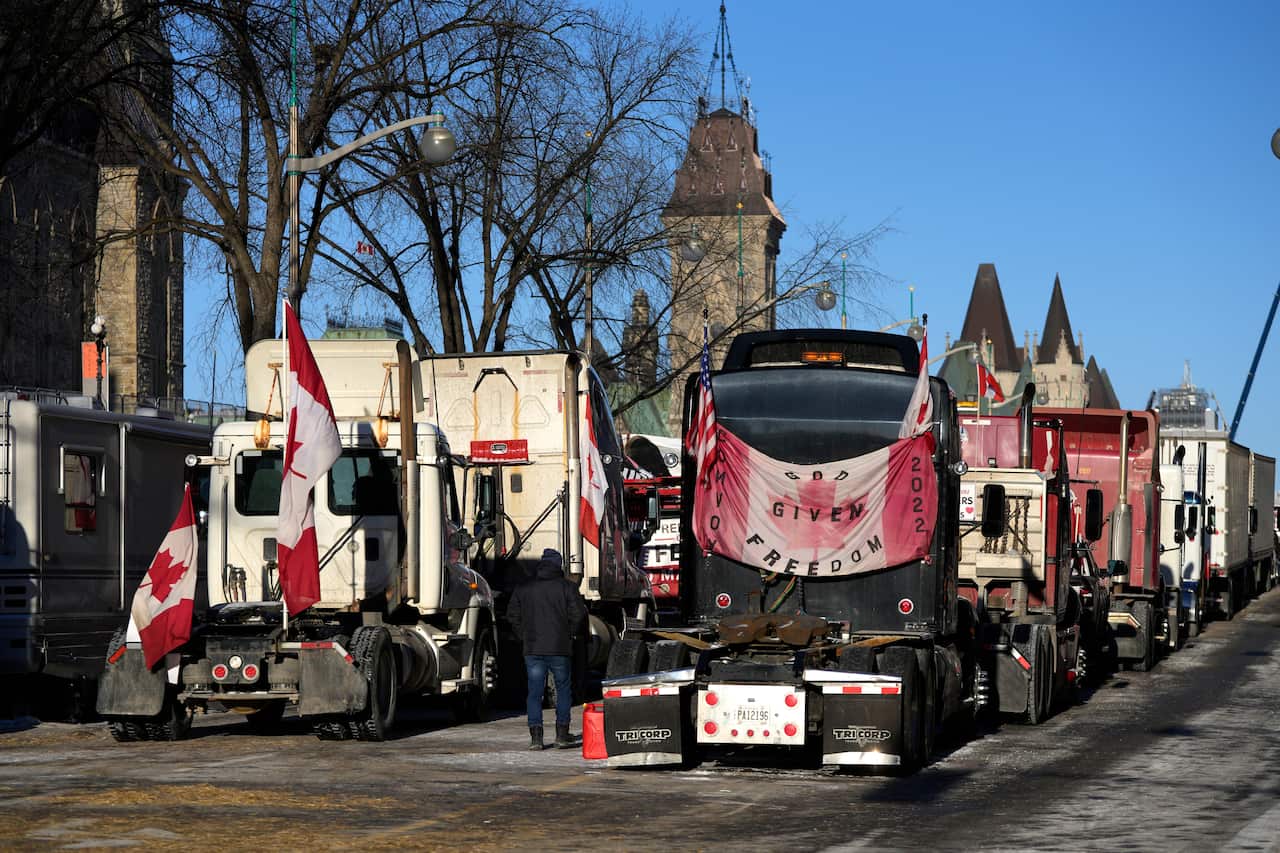 A person walks among trucks flying Canadian flags