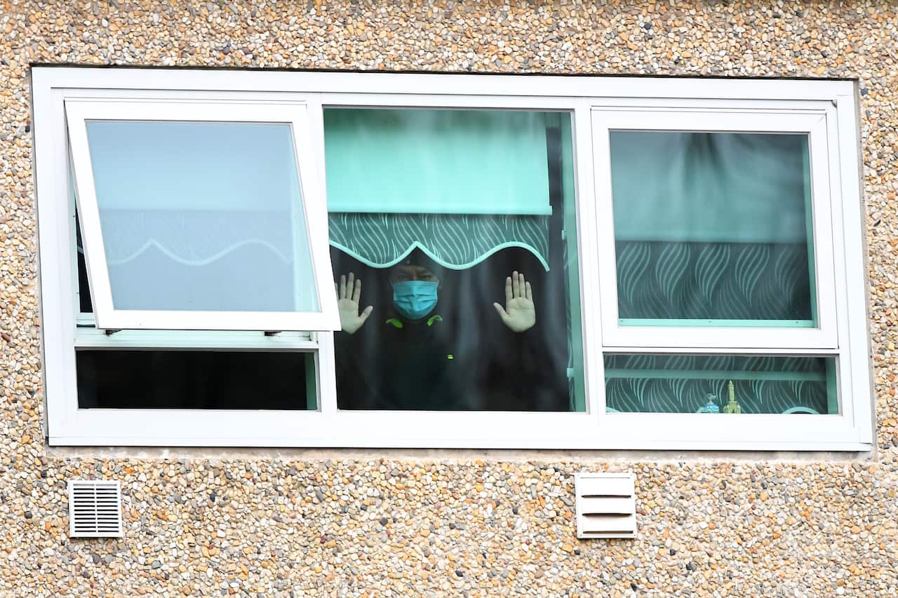 A man gestures from inside his apartment during the hard lockdown of nine public housing towers in Melbourne. 