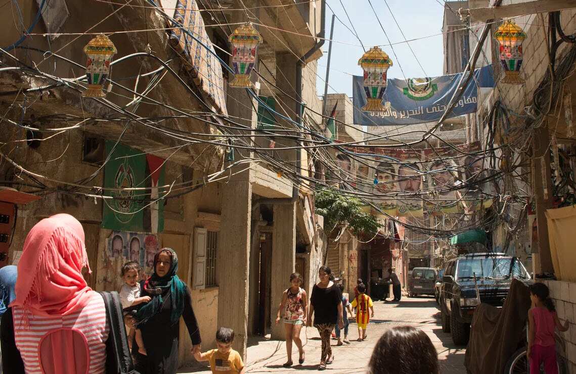 One of the main streets of the camp. Ramadan decorations are hanging with the perilous electricity cables. 