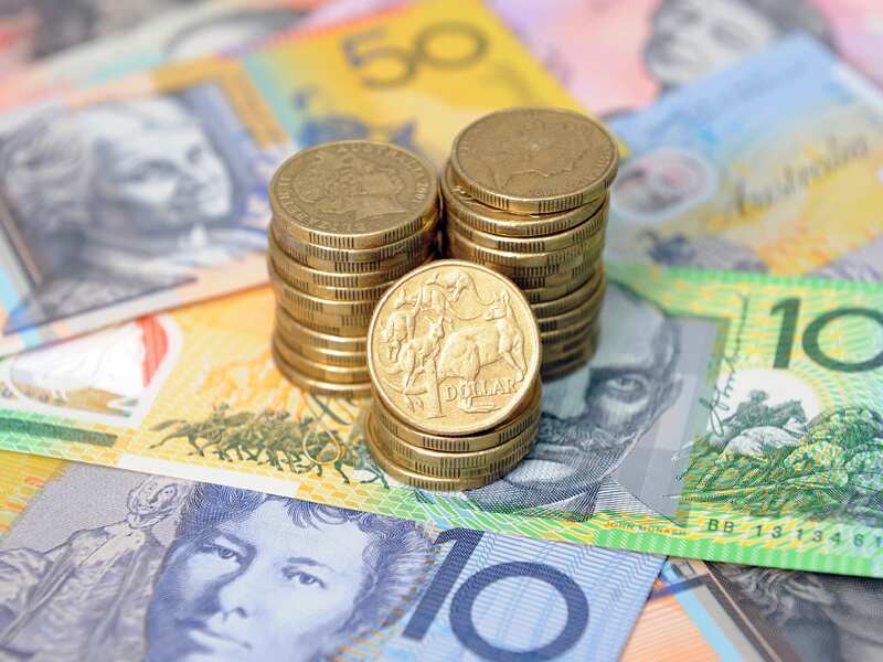 A stack of coins is placed over Australian currency notes.