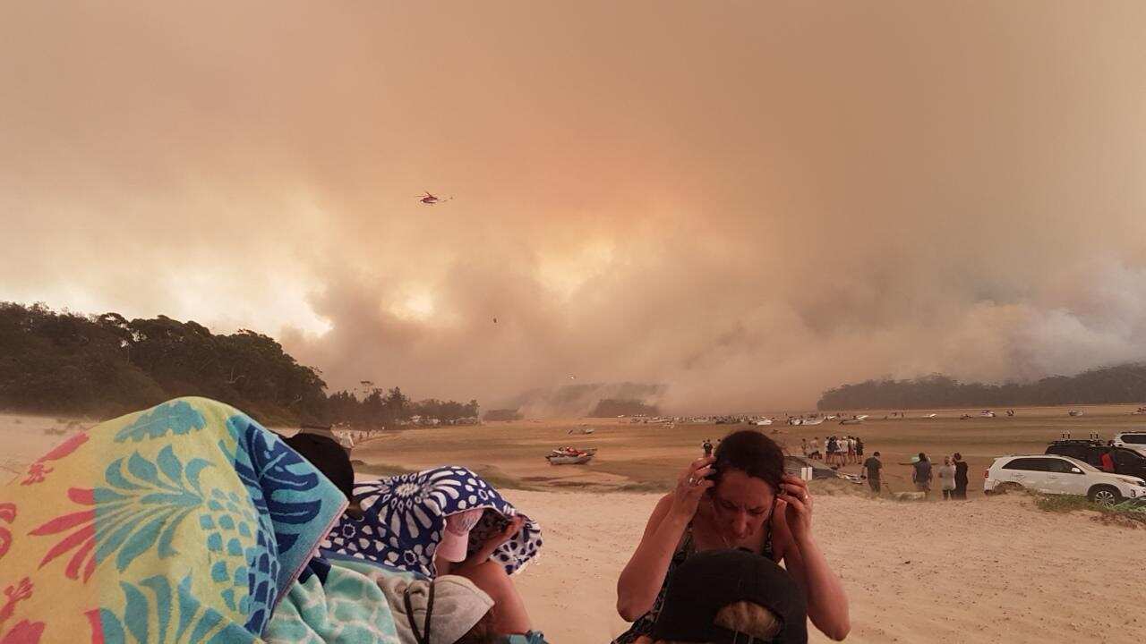 Locals and visitors to Lake Conjola fled to the beach when bushfires approached on 31 December. 