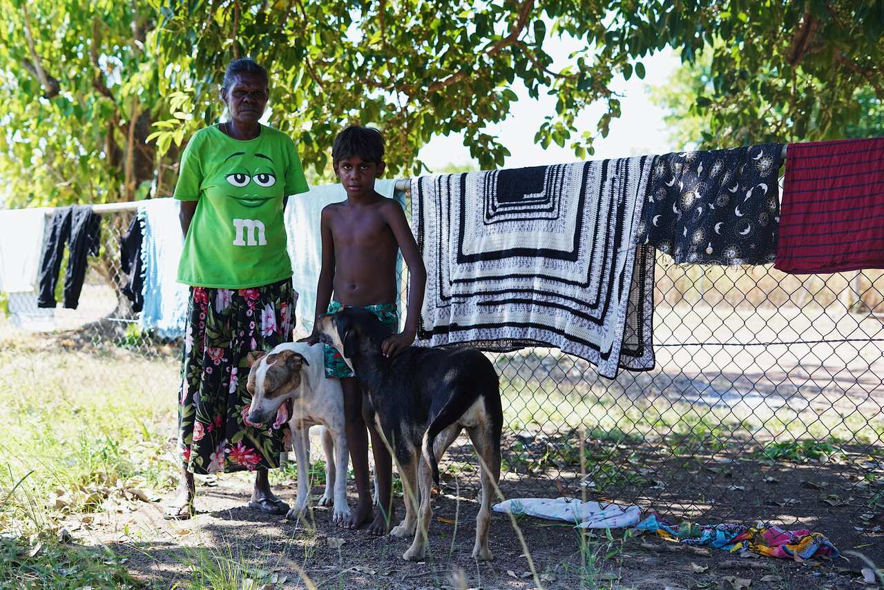 Woman and boy stand at a home in Bagot 