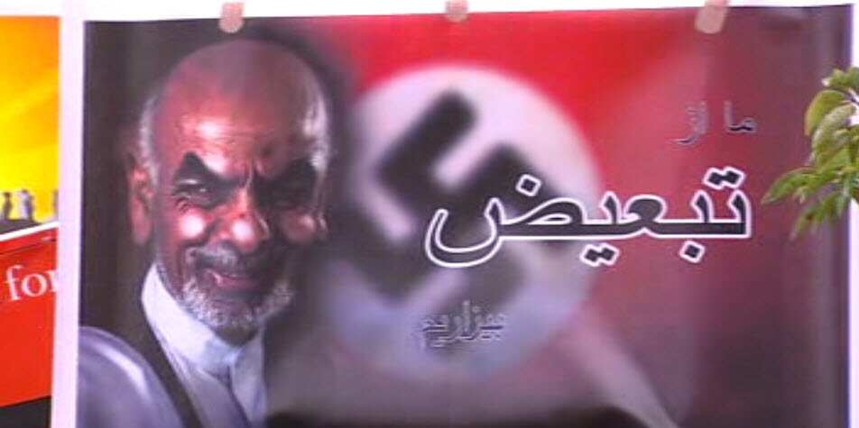 A protest sign depicting Afghan president Ashraf Ghani overlayed on the Nazi swastika symbol.