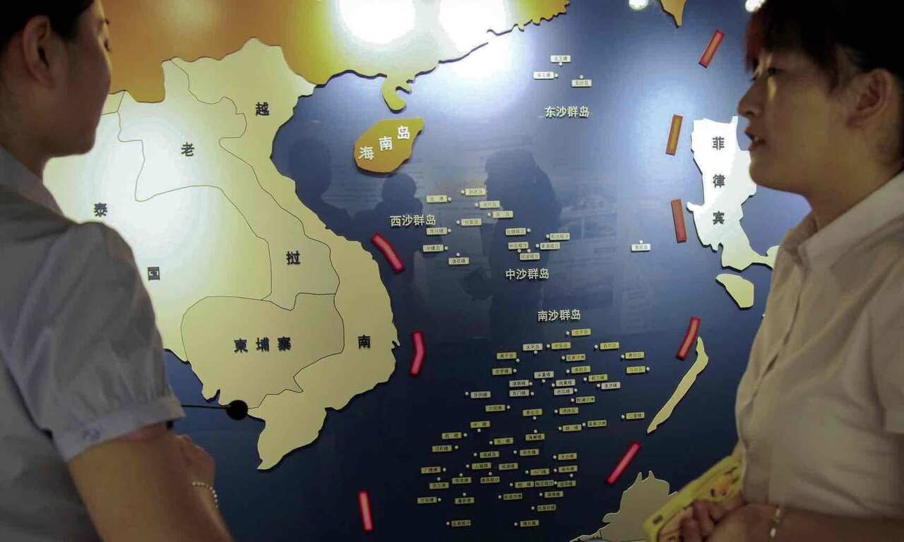 Workers chat near a map of South China Sea on display at a maritime defense educational facility in Nanjing in east China’s Jiangsu province.