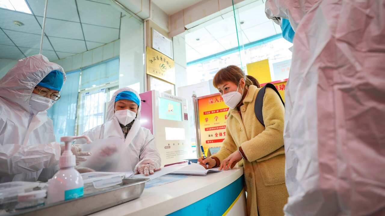 Medical workers in protective gear talk with a woman suspected of being ill with a coronavirus at a community health station in Wuhan