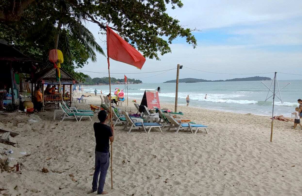 A man raises a red flag indicating rough weather conditions in Chaweng beach, Koh Samui, Thailand