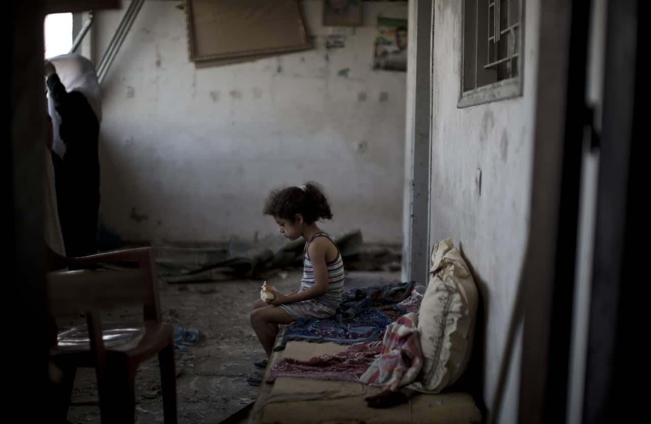A Palestinian girl sits and eats in the rubble of her destroyed home following an overnight Israeli strike on Gaza City.
