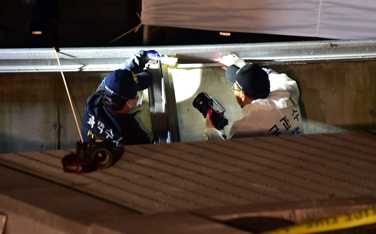 South Korean National Forensic Service members check a broken ventilation grate
