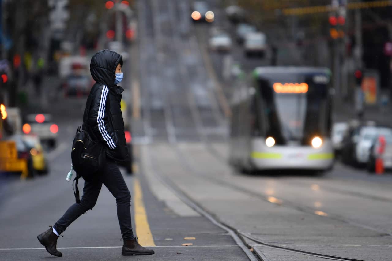 Woman in a mask crosses a Melbourne street.