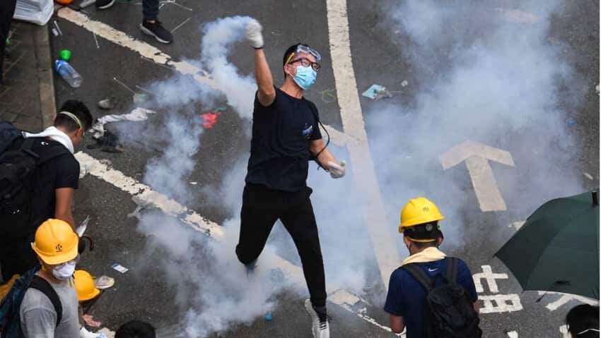 A protester throws back a tear gas during clashes with police outside the government headquarters in Hong Kong.