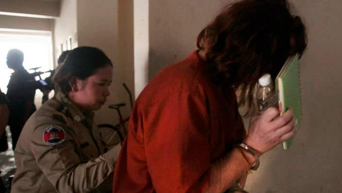 Tammy Davis-Charles, right, charged with providing commercial surrogacy services, hides her face as she enters to the Phnom Penh Municipal Court 