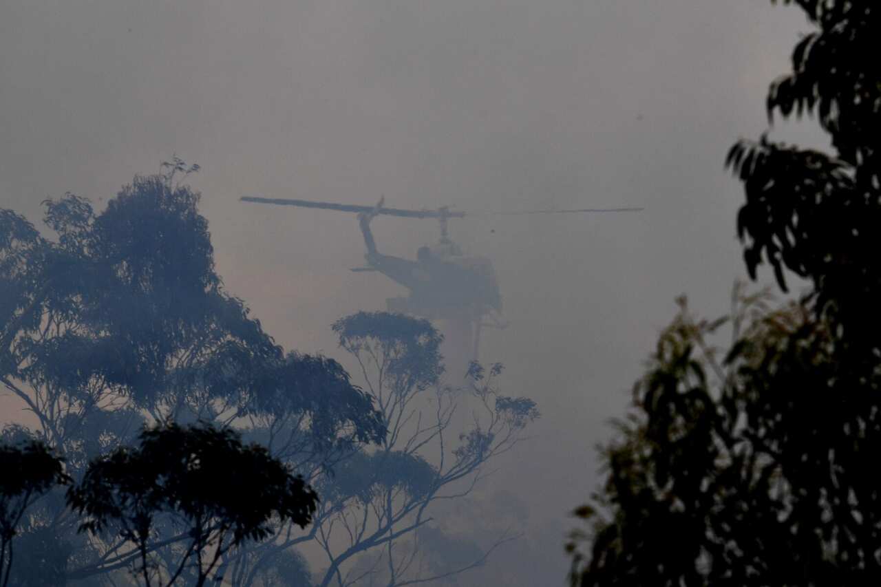 A water bombing helicopter helps to contain the Gospers Mountain Fire