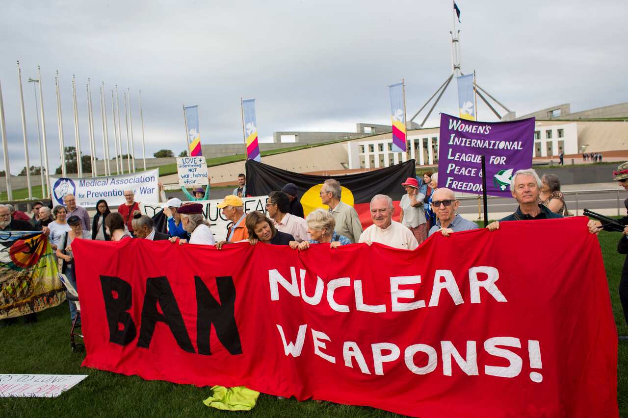 Protestors hold banners during a protest condemning Australia's absence at current nuclear weapons treaty negotiations in New York outside Parliament House in Canberra, Tuesday, March 28, 2017. (AAP Image/Sean Davey) NO ARCHIVING