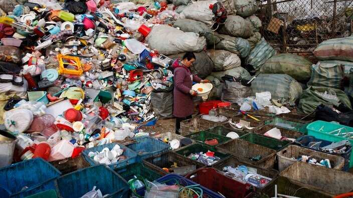 A worker sorts used plastics at a trash collection site in Changping district of Beijing, China