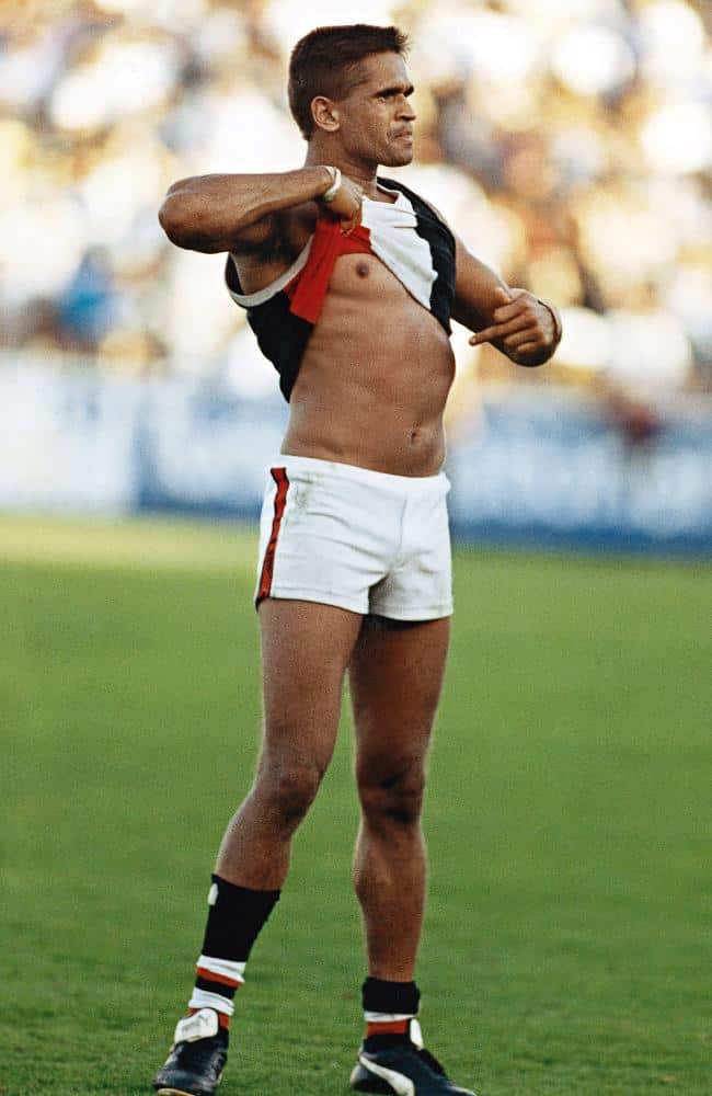Football player Nicky Winmar lifts his top and points at his stomach in response to racist abuse.