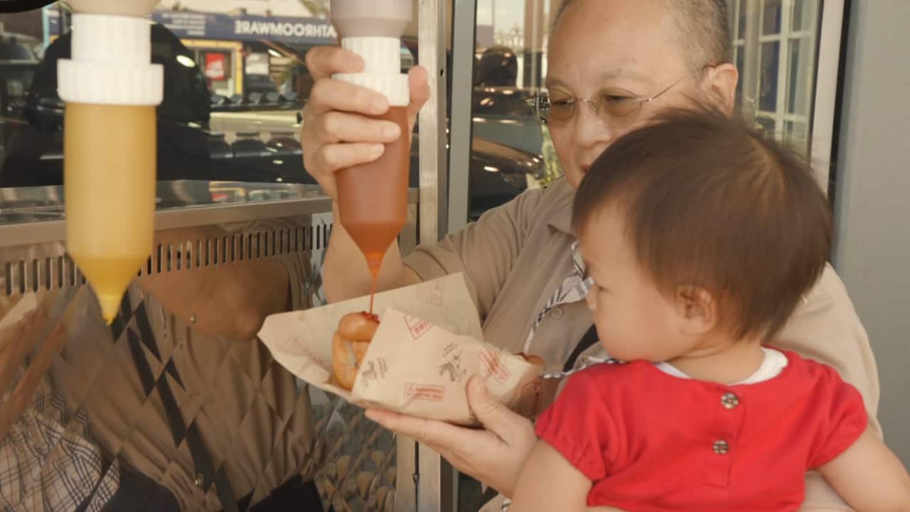 A customer enjoys a hot dog at one of Yummy Dogs catering events