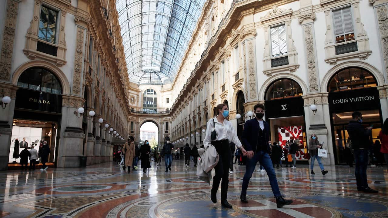 People wearing a sanitary mask walk in downtown Milan, Italy, Saturday, Oct. 17, 2020. 