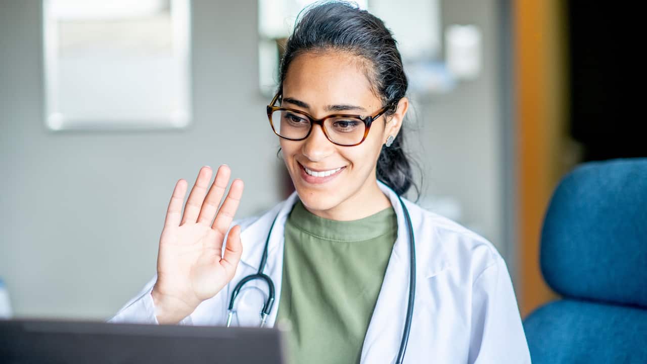 Female doctor waving to telehealth patient 