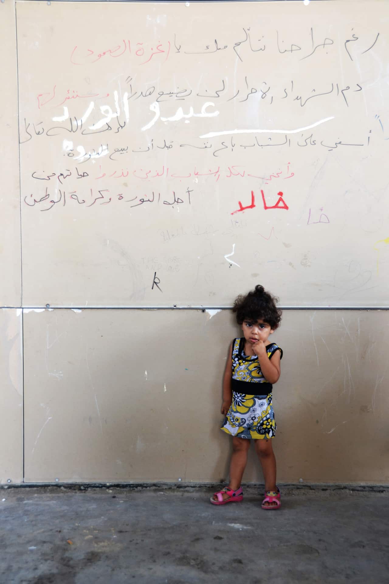 A Palestinian girl stands in front of pro-Gaza graffiti that reads: 'Despite our injuries, we support Gaza. The blood of martyrs will not be wasted.' (Photo: Matthew Clayfield)