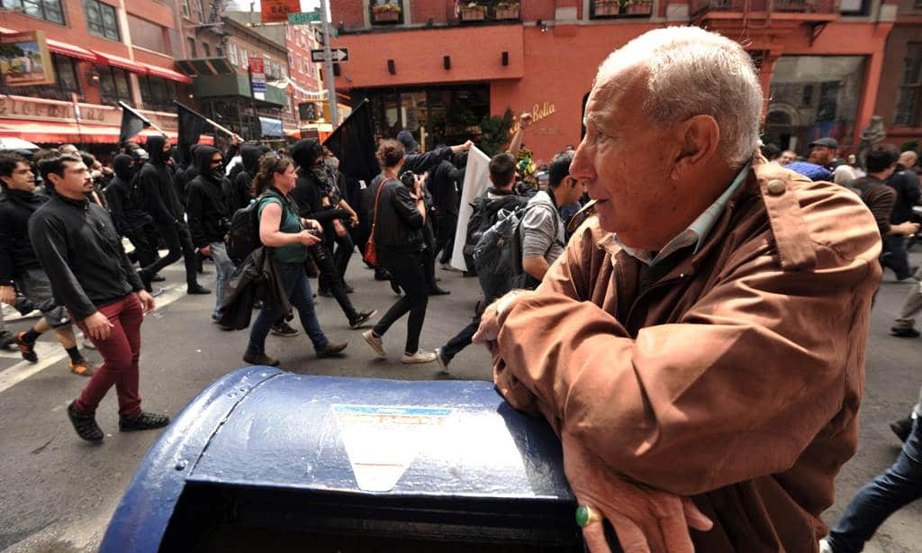 A man watches Occupy Wall Street protesters march through a Chinatown street as the movement joins with activists groups for May Day demonstrations May 1, 2012 in New York. (AAP)