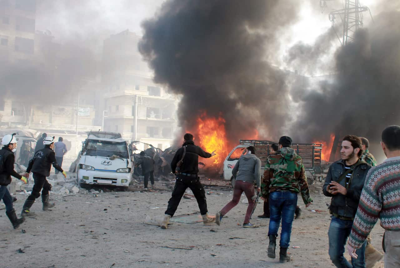 Emergency personnel and civilians are seen at the site of a barrel bomb attack reportedly dropped by government forces which struck a minibus carrying civilians in the northern Syrian city of Aleppo on January 21, 2014. (AAP)