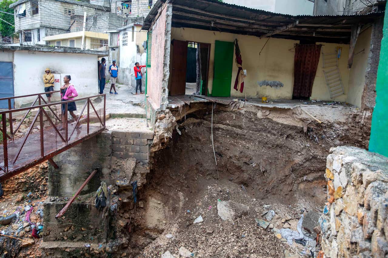 A woman walks on a bridge near a house damaged by a river after the passing of Tropical Storm Laura in Port-au-Prince, Haiti (AAP)