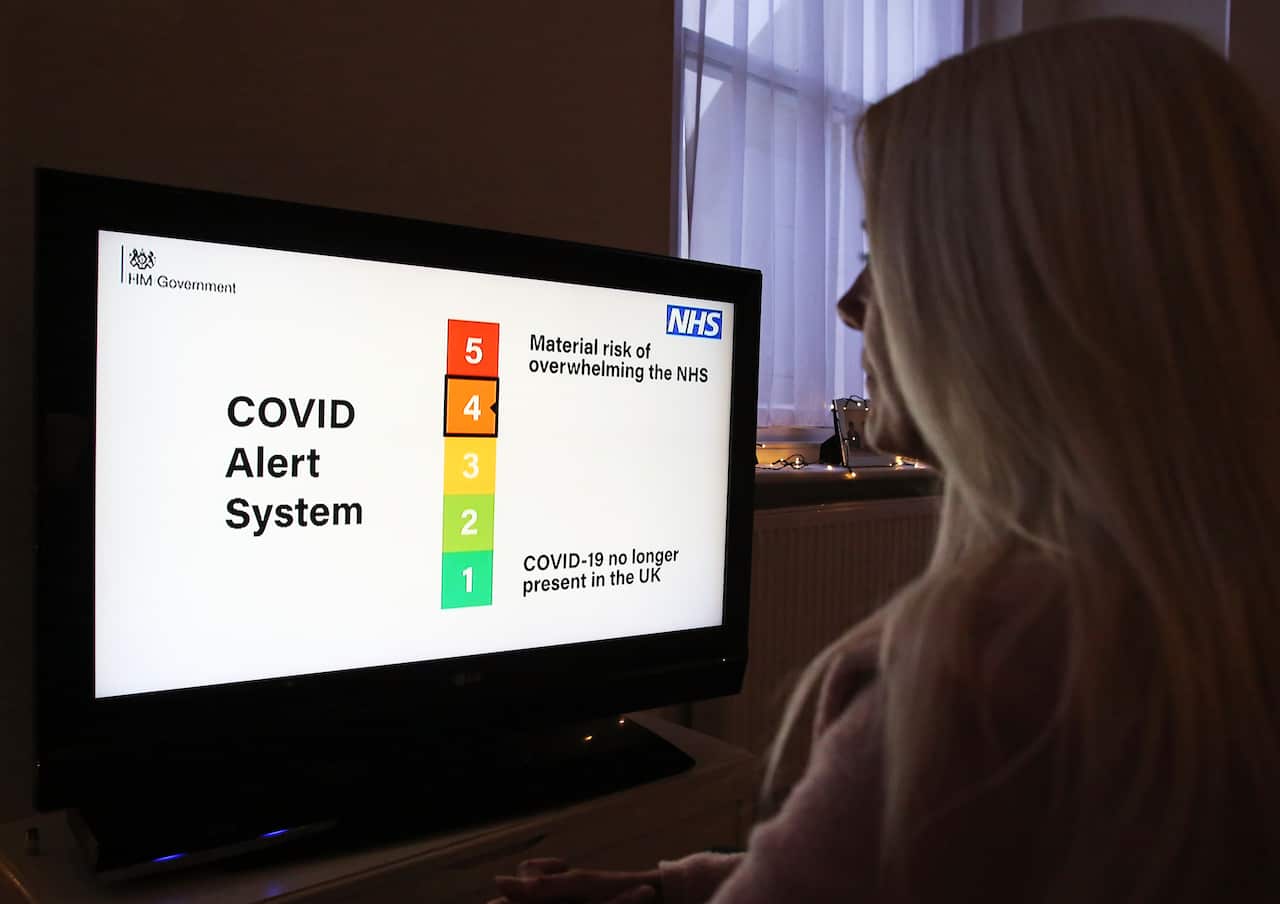 A woman watches the Covid Alert System during Boris Johnson's speech to the nation (AAP)