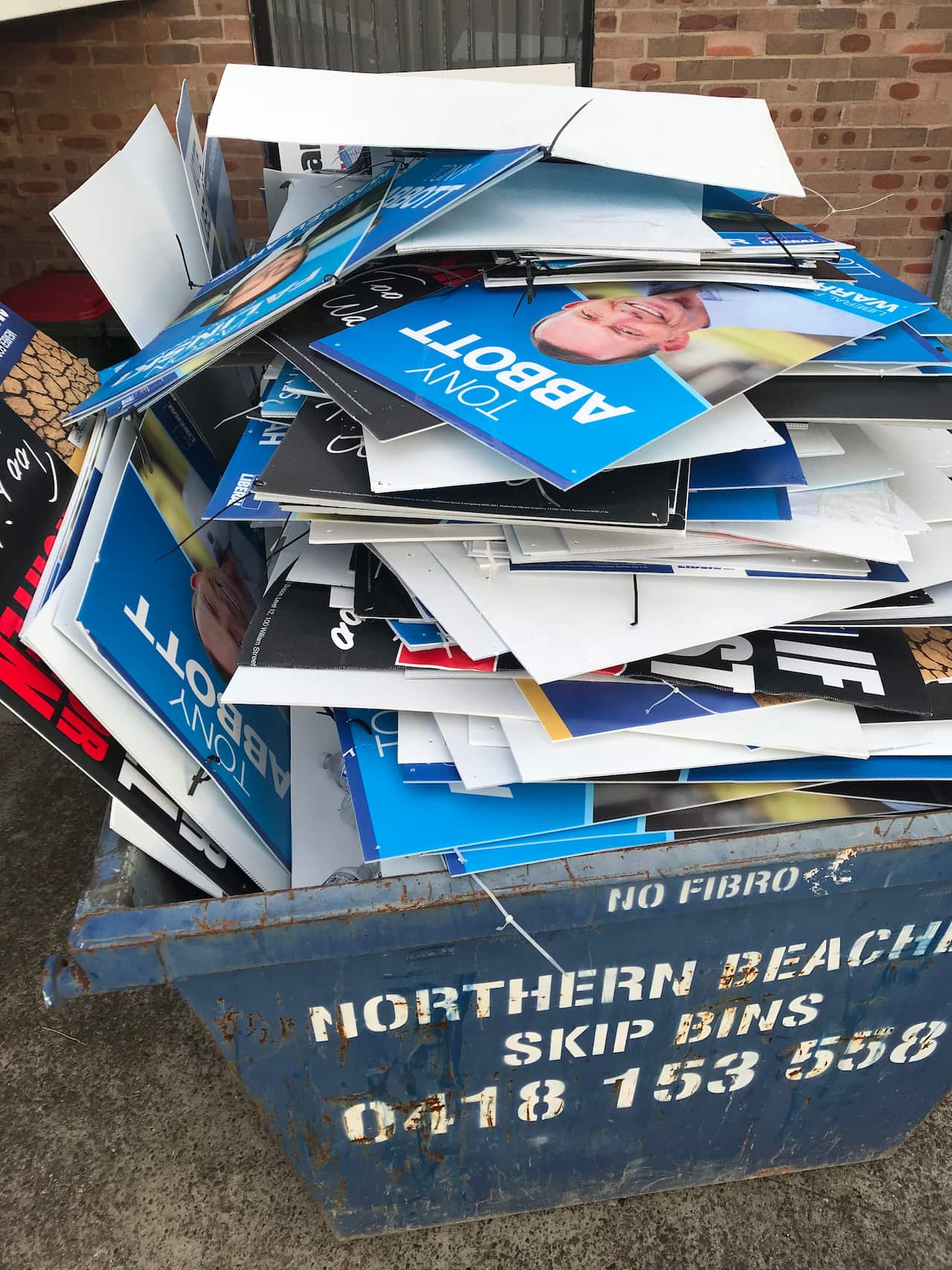 A stack of Tony Abbott placards loaded into a skip bin after independent Zali Steggall won his seat of Warringah.