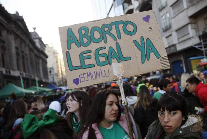 A pro-choice activist holds a sign that reads in Spanish "Legal abortion now".