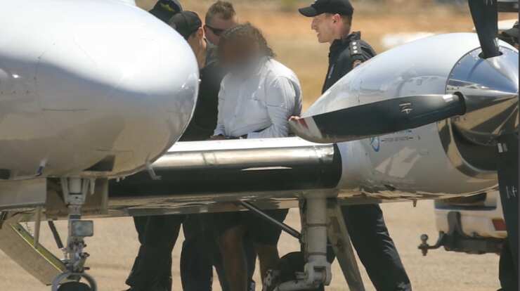 Terence Darrell Kelly is escorted by police onto a charter flight. 