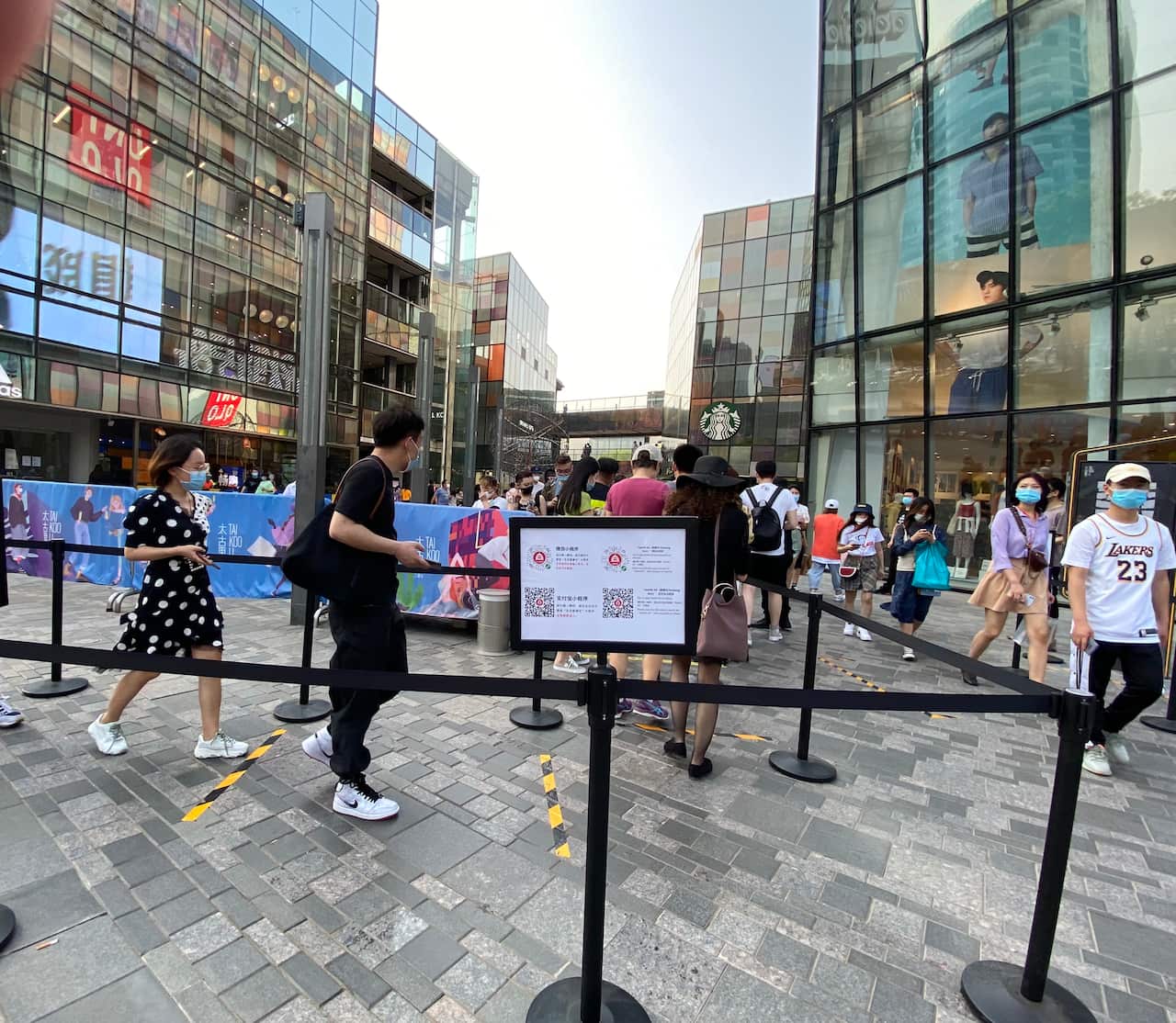 People queue up to log in and show their Health Kit QR Code so that they can enter the popular Sanlitun shopping district.