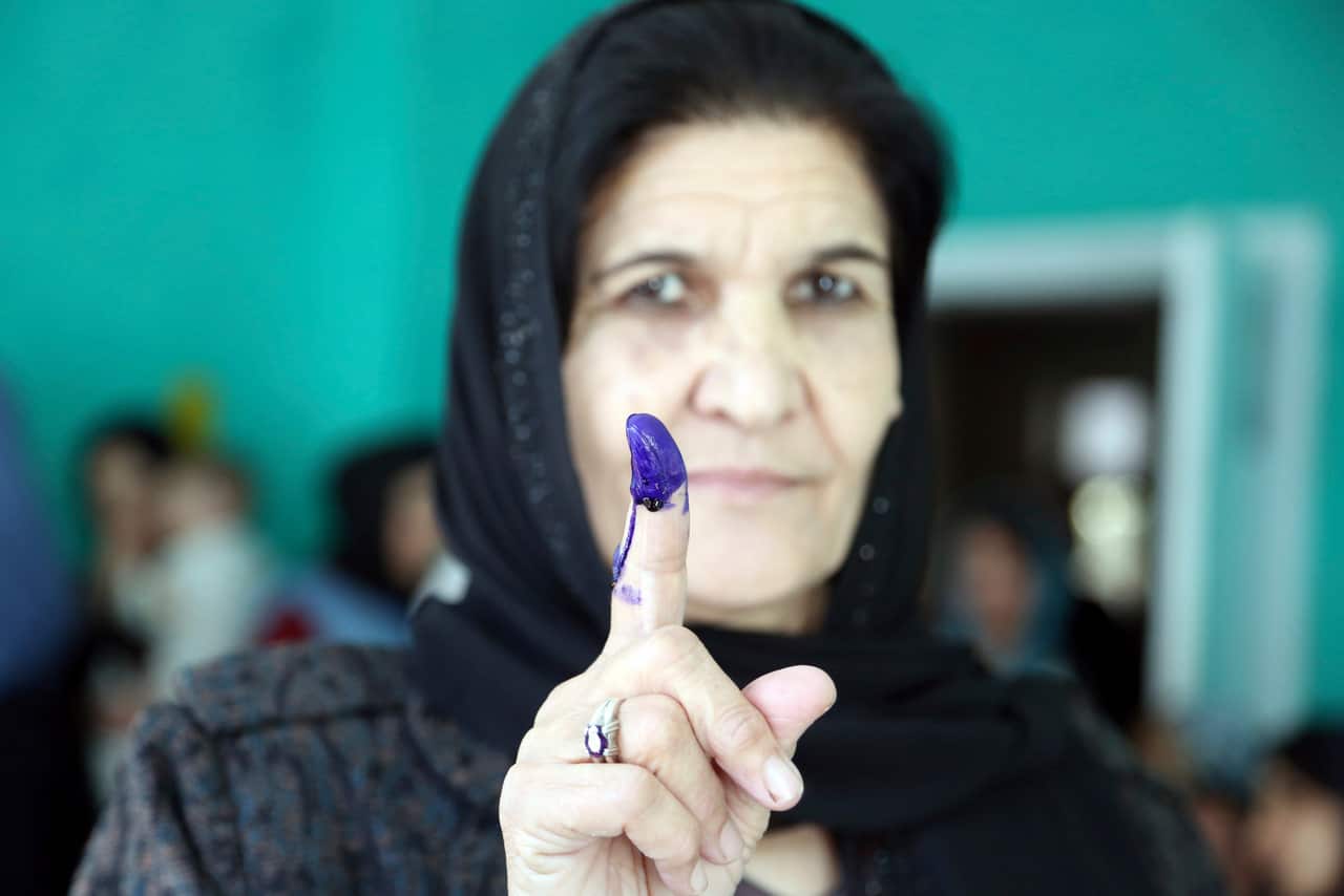 An Afghan woman shows her inked finger after casting her vote at a polling station during the Parliamentary elections in Kabul.