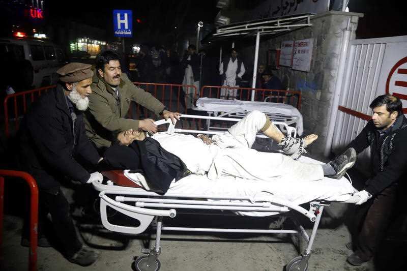 Afghan health workers carry an injured man to an emergency hospital after a truck bomb blast in Kabul, Afghanistan.