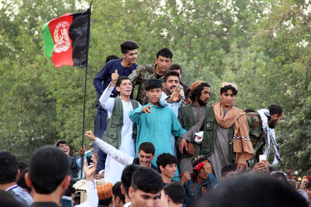 People greet alleged militants and Afghan security officials.