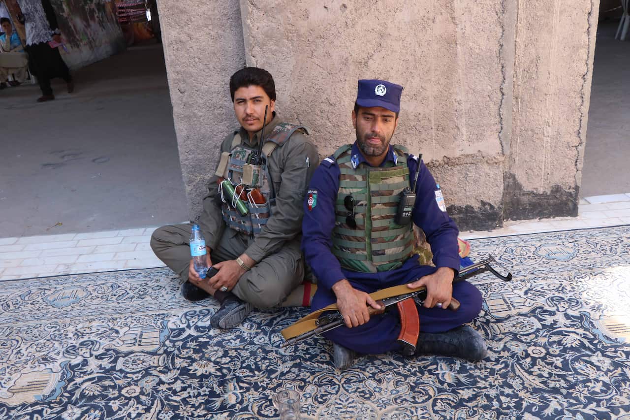 Afghan police officers sit as they guard a polling station during the Presidential elections in Herat, Afghanistan.