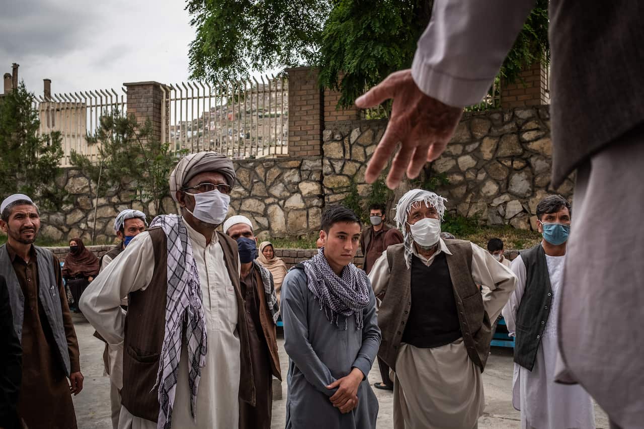 Ghulam Sakhi, second from right, listening as a hospital staff member explains why families must wait to pick up the babies at Ataturk hospital in Kabul, Afghanistan, Wednesday, May 13, 2020. (Jim Huylebroek/The New York Times)