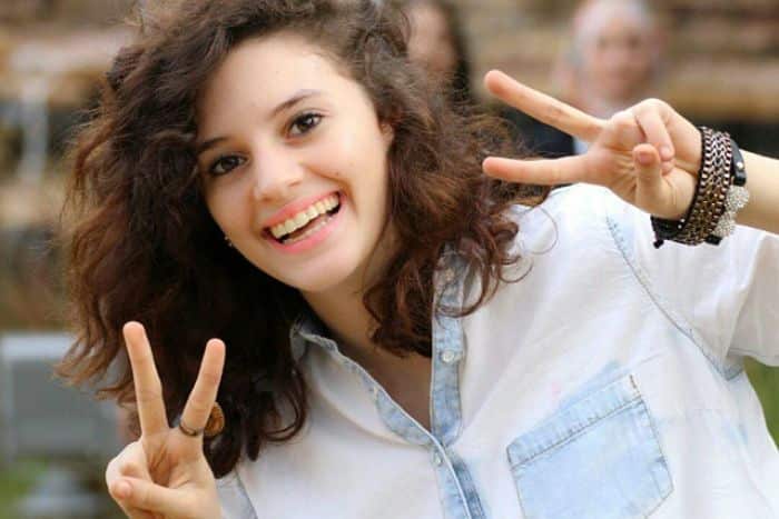 A young woman smiling and making peace symbols with her fingers. 