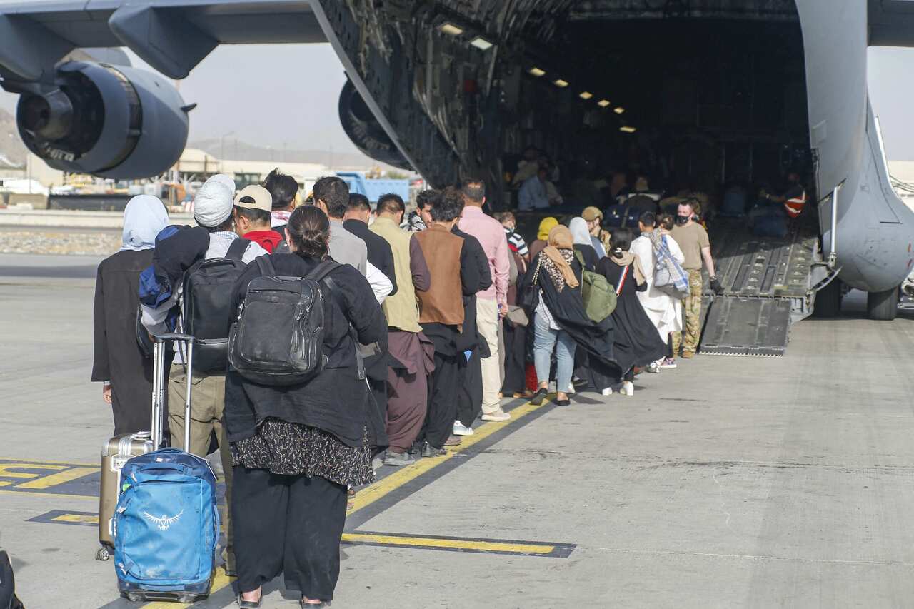 Evacuees stage before boarding a US C-17 Globemaster III during an evacuation at Hamid Karzai International Airport on 18 August 2021.