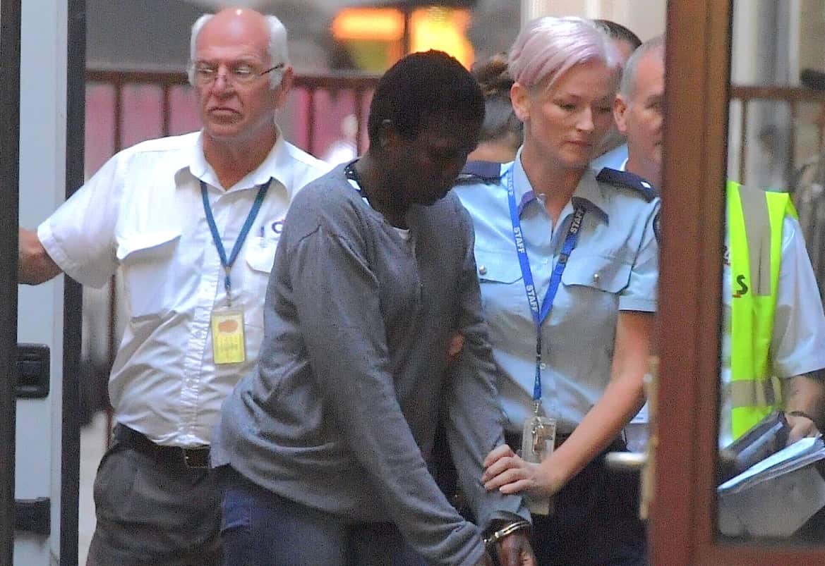 A woman is handcuffed being escorted by a police officer 