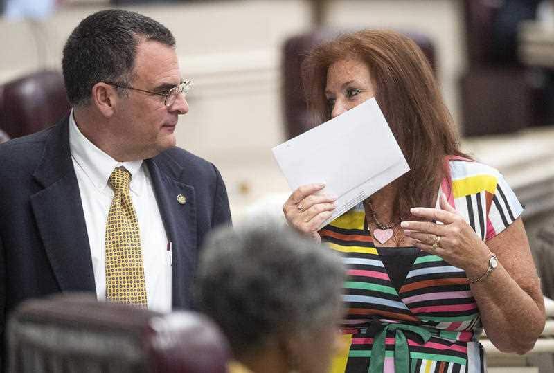 Rep. Terri Collins, right, chats with Rep. Chris Pringle on the house floor at the Alabama Statehouse ahead of the vote.